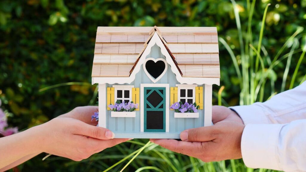 Close-up of hands holding a detailed miniature house model, symbolizing goals of homeownership.